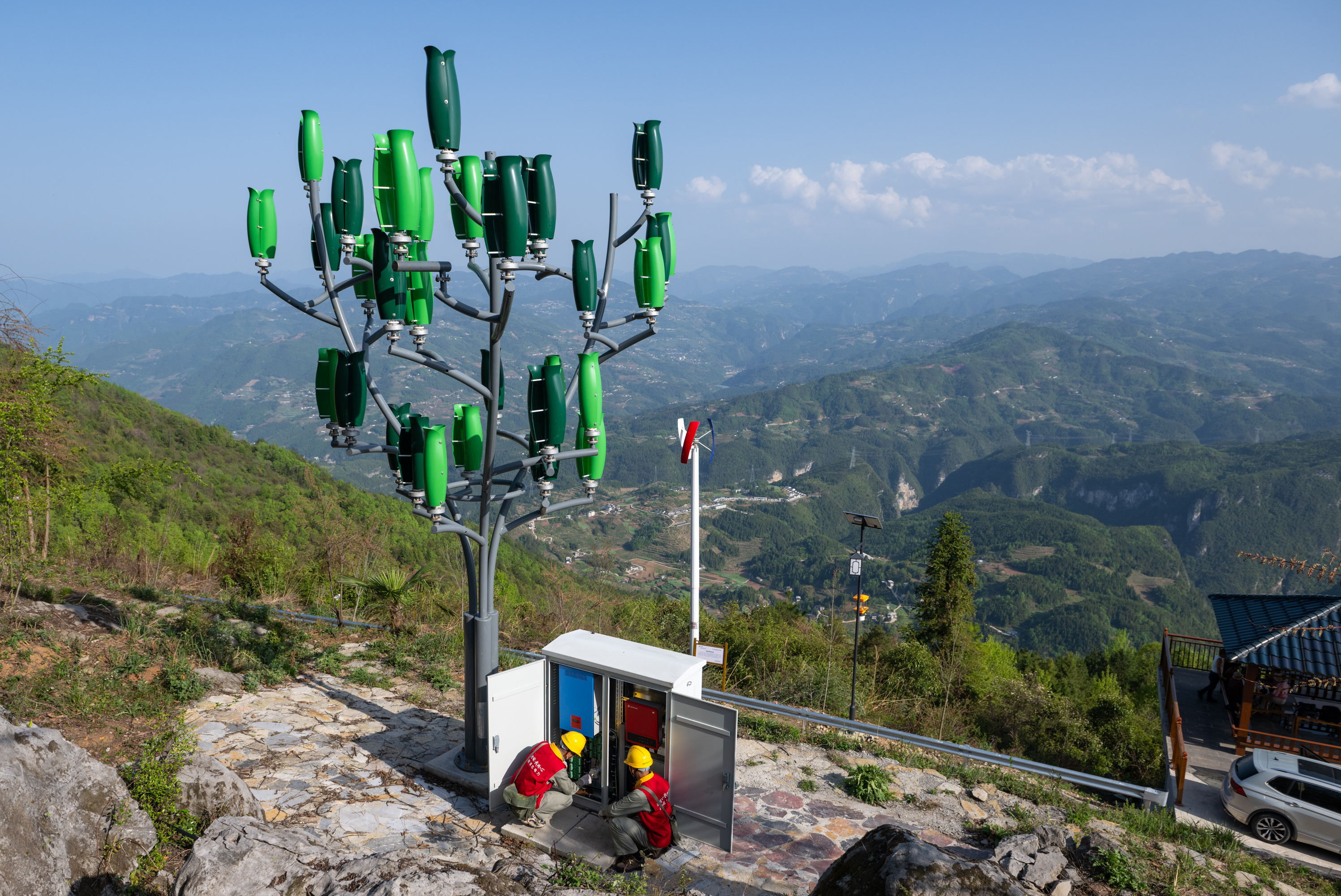 A staff of State Grid Badong Power Supply Company is checking the breeze power generation equipment in Tudianzi Village. (Photo by Lei Yong/Xinhua)