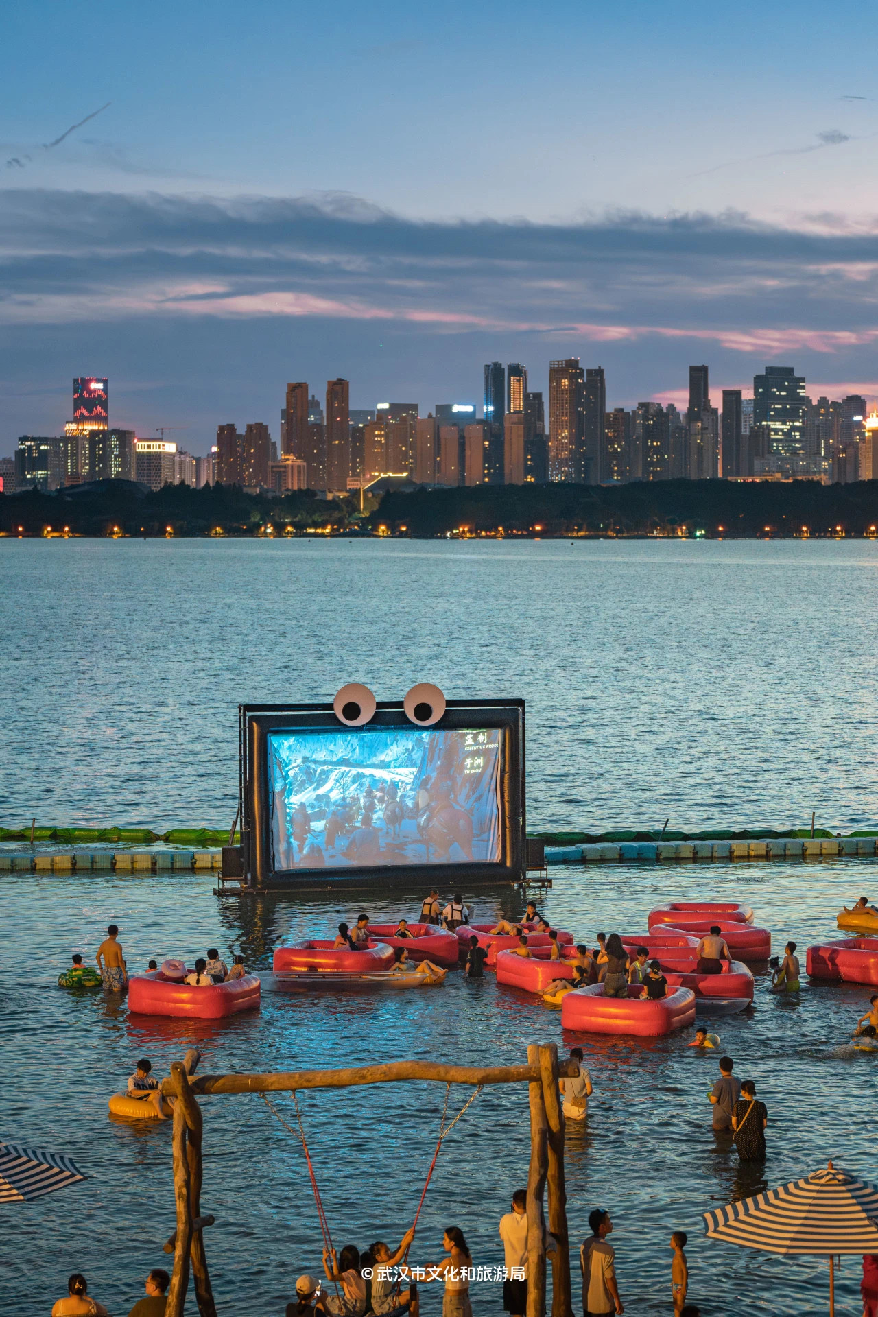Floating cinema at dusk with city lights.